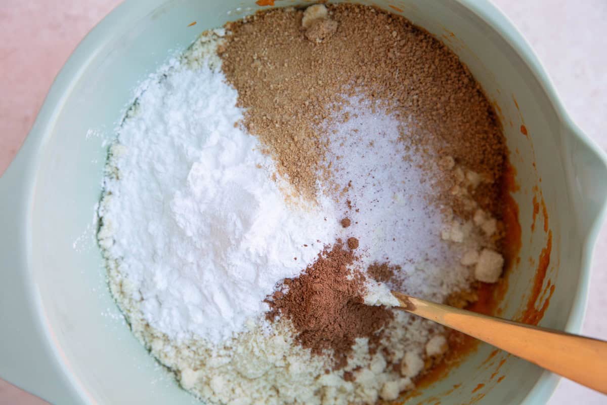 Dry ingredients on top of wet ingredients in a mixing bowl to make pumpkin bread.