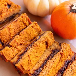 Pumpkin cinnamon swirl bread cut into individual slices with pumpkins in the background.