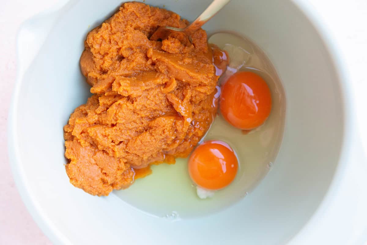 Pumpkin puree and eggs in a mixing bowl to make pumpkin bread.