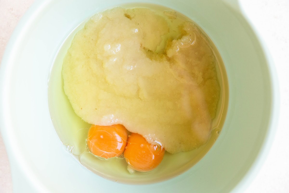 Applesauce, avocado oil, and eggs in a mixing bowl, ready to be stirred together.