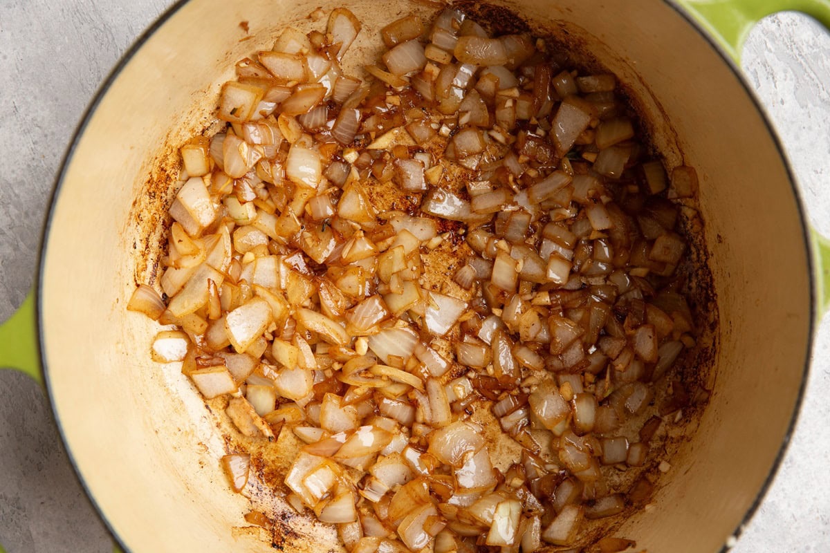 Onion and garlic cooking in a large pot to make soup.