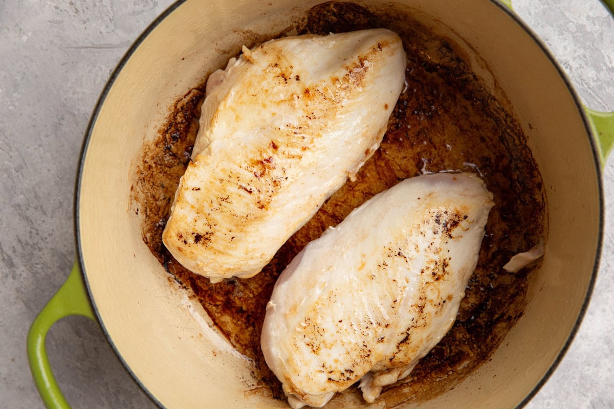 Chicken searing in a large pot.