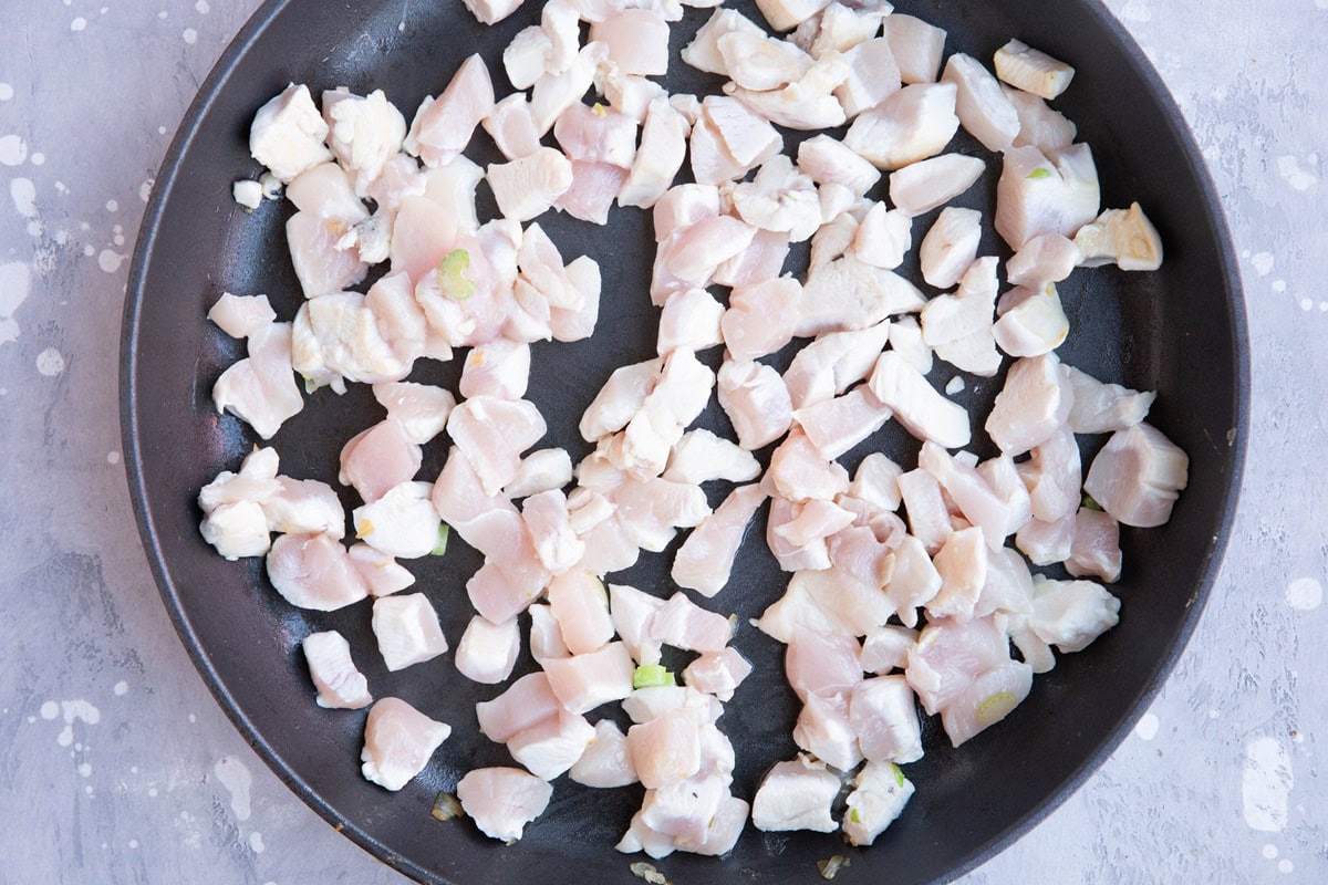 Chicken pieces browning in a skillet.