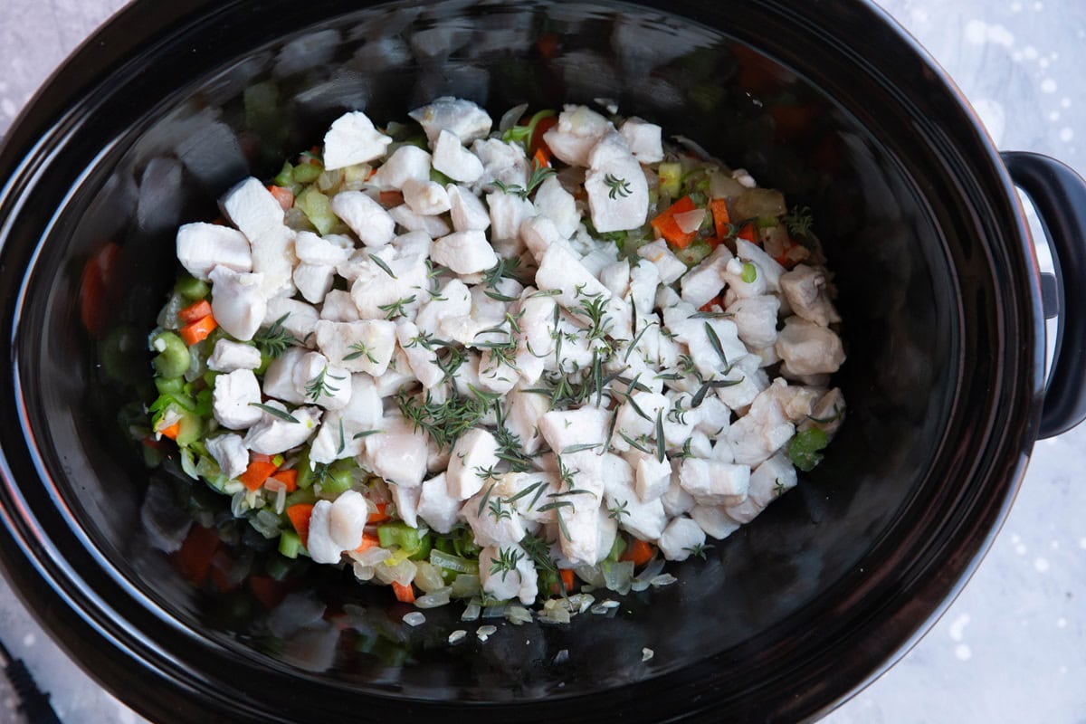 Crock pot full of vegetables and chopped chicken.