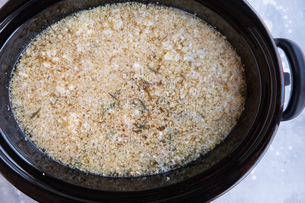 Crock pot full of vegetables, broth, chicken, and cauliflower rice.