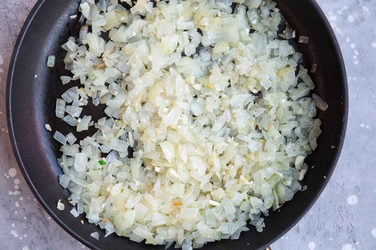 Skillet full of sauteed onion to make soup.