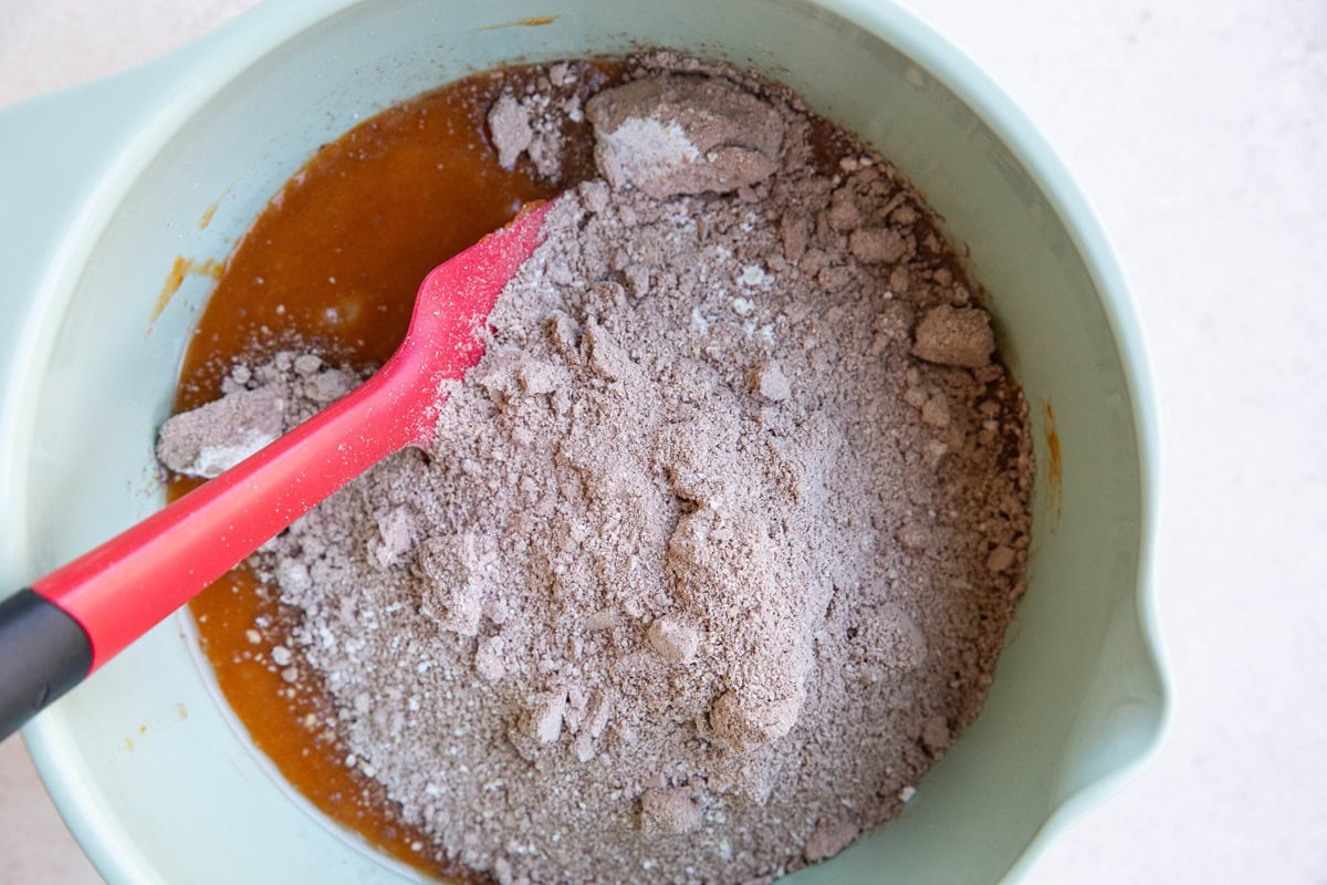 Mixing bowl of pumpkin mixture and dry ingredients, to be mixed together to make muffins.