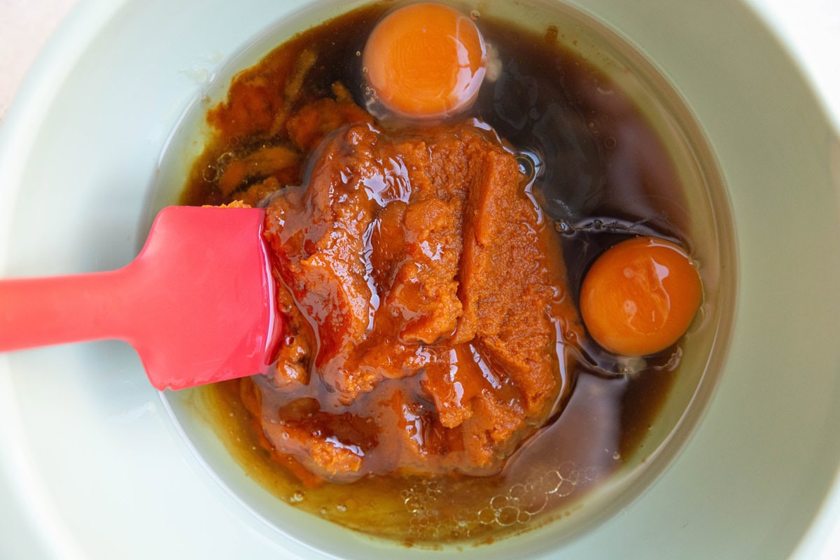 Mixing bowl with pumpkin puree, eggs, pure maple syrup, and oil for muffins.