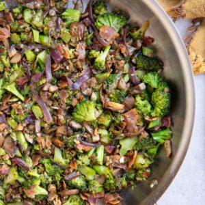 Stainless steel skillet full of sauteed broccoli and mushrooms, ready to eat.