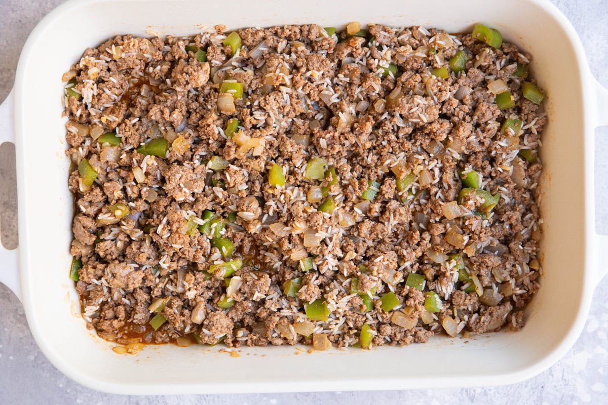 Casserole dish full of ground beef, rice, onion, and bell pepper.