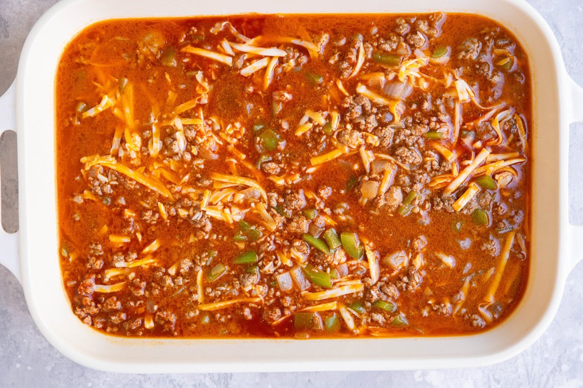 Casserole dish full of ground beef, enchilada sauce, cheese, and rice.