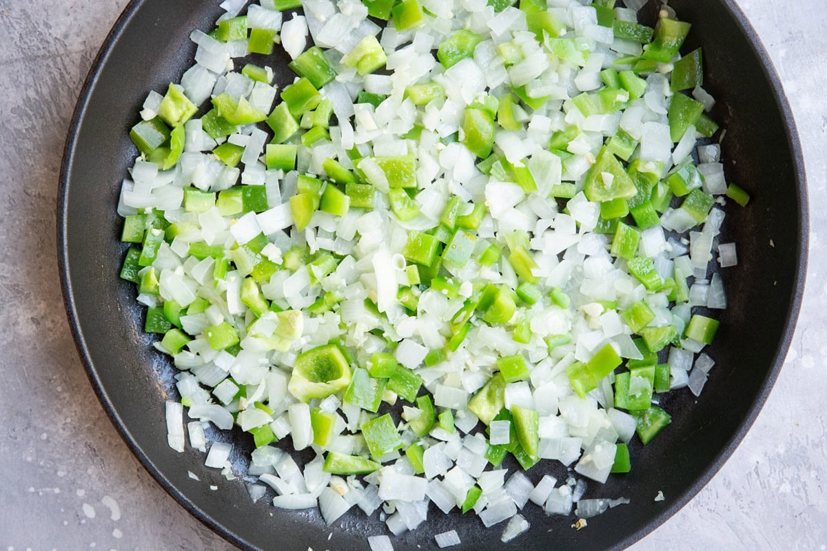 Onion and bell pepper cooking in a skillet