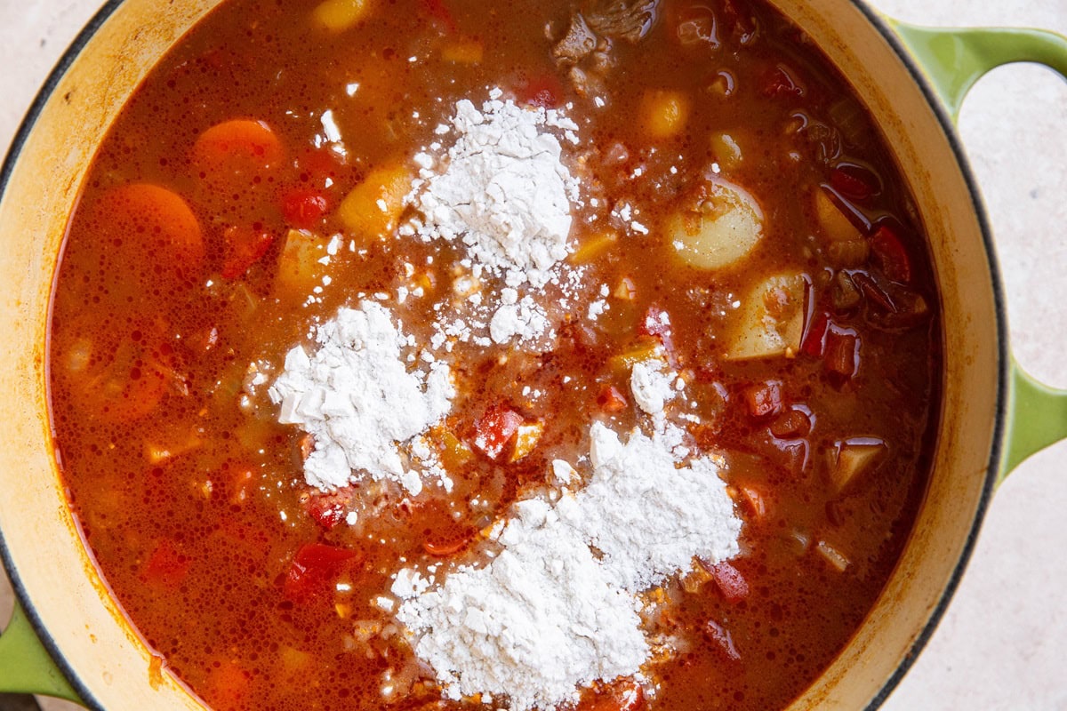 Big pot of soup with flour added in on top.