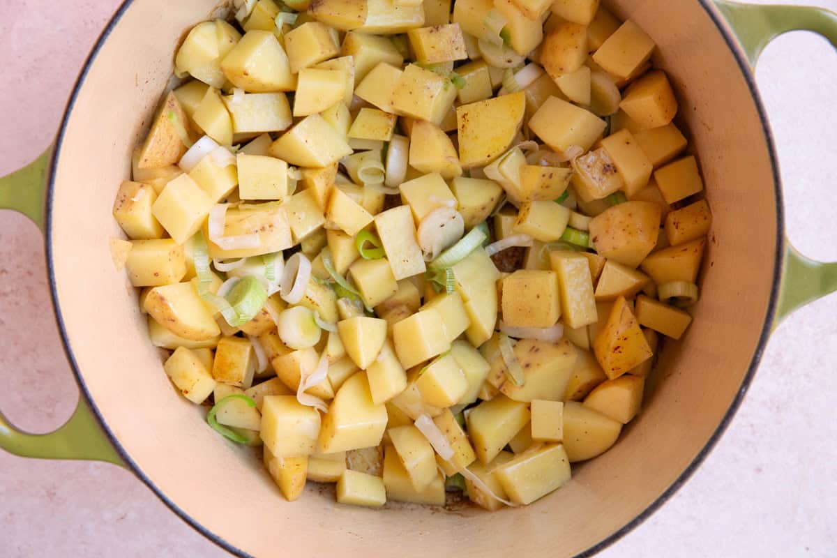 Large dutch oven filled with leeks and potatoes to make potato leek soup