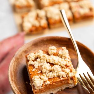 Hand holding a plate with a sweet potato bar and a fork.