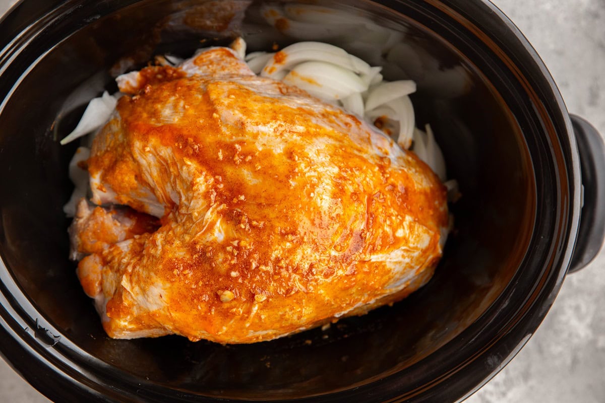 Bone-in turkey breast lathered with garlic butter in a slow cooker.