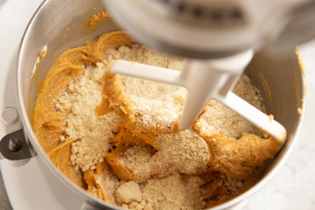 Almond flour on top of wet ingredients in a stand mixer to make grain-free peanut butter cookies.