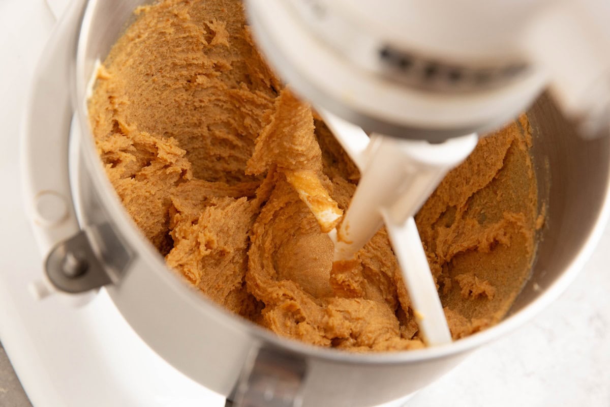 Butter, peanut butter, and sugar mixed together in a stand mixer to make peanut butter cookies.