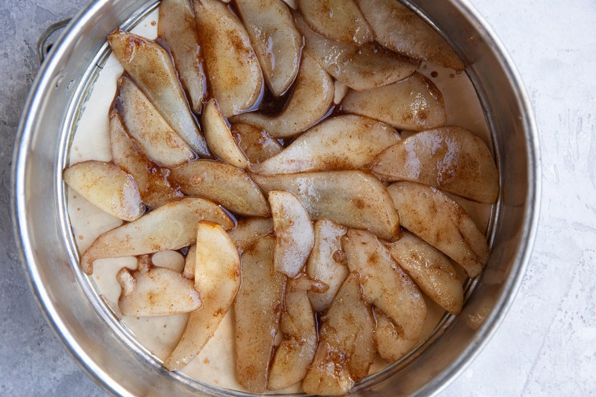 Cake pan with sliced softened pears arranged in a circle.