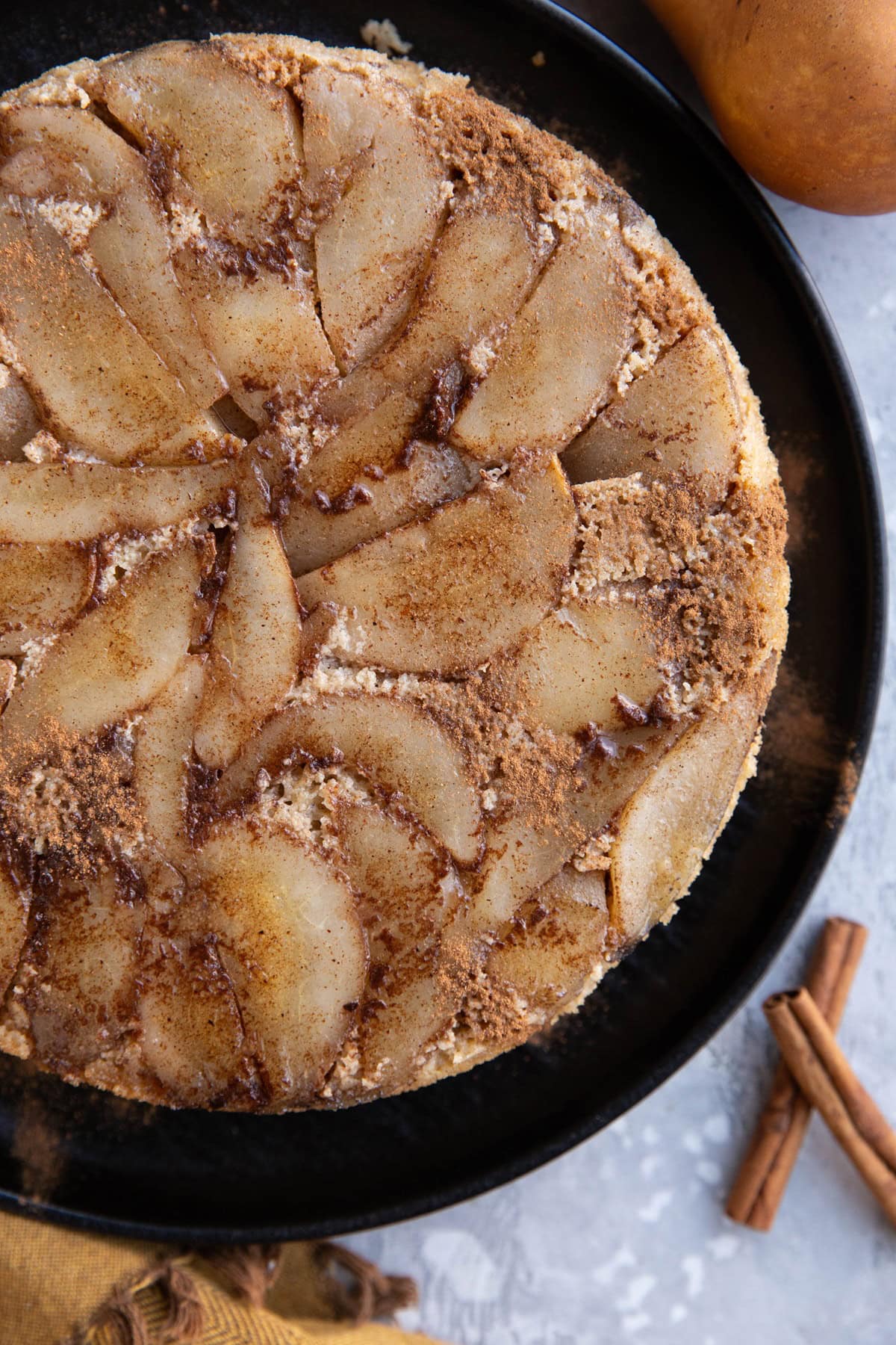 Pear cake on a black plate, ready to slice.