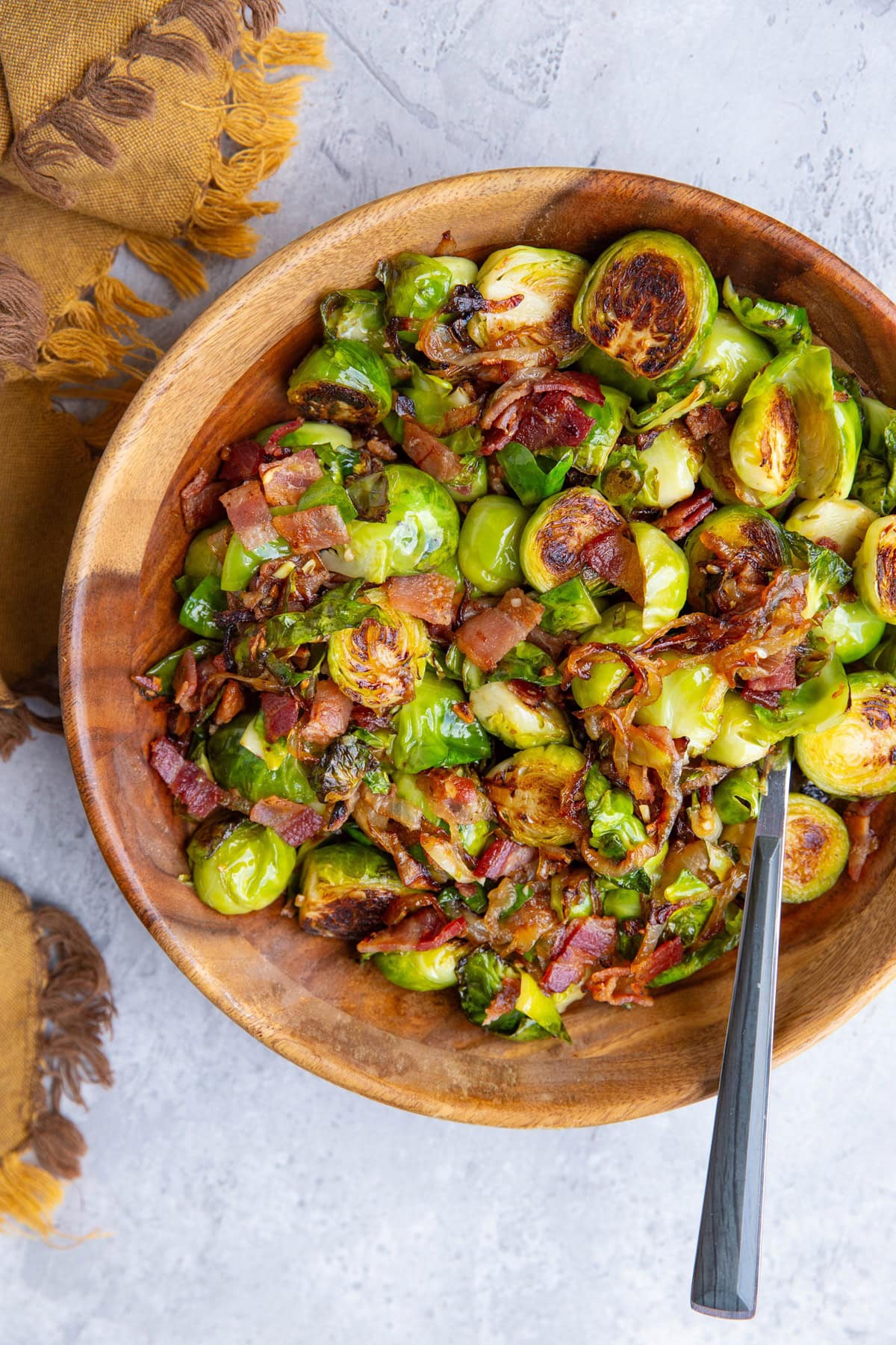 Wooden bowl full of brussel sprouts with caramelized onions and bacon.