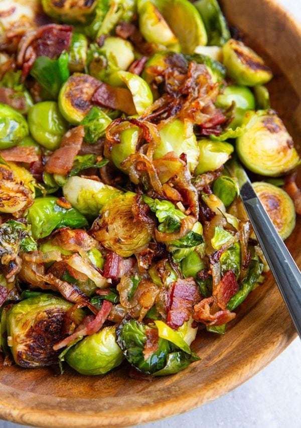 Wooden bowl of brussel sprouts with caramelized onions and bacon.