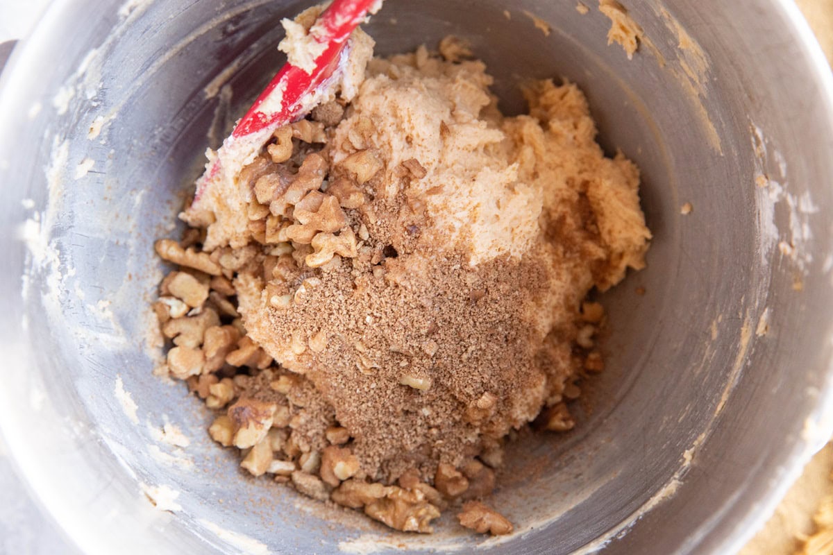 Coffee cake muffin batter in a large bowl with cinnamon sugar walnuts being mixed in.