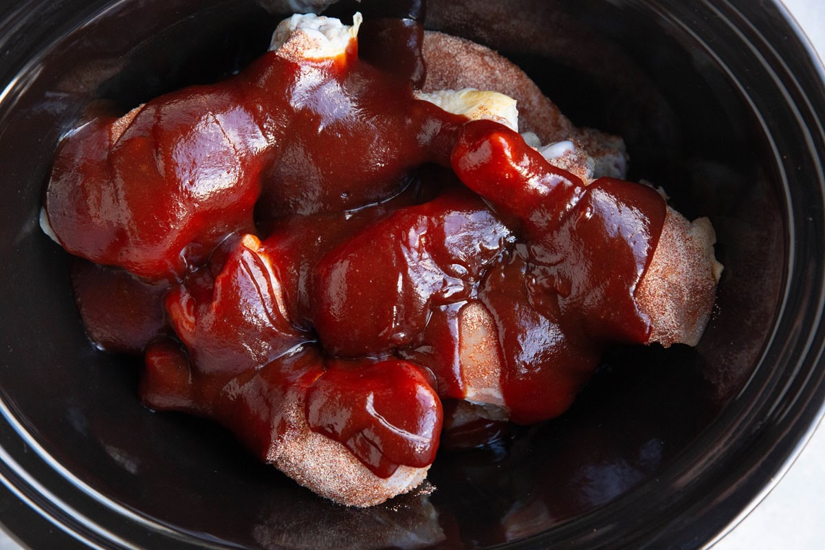 Crock pot full of chicken and bbq sauce.