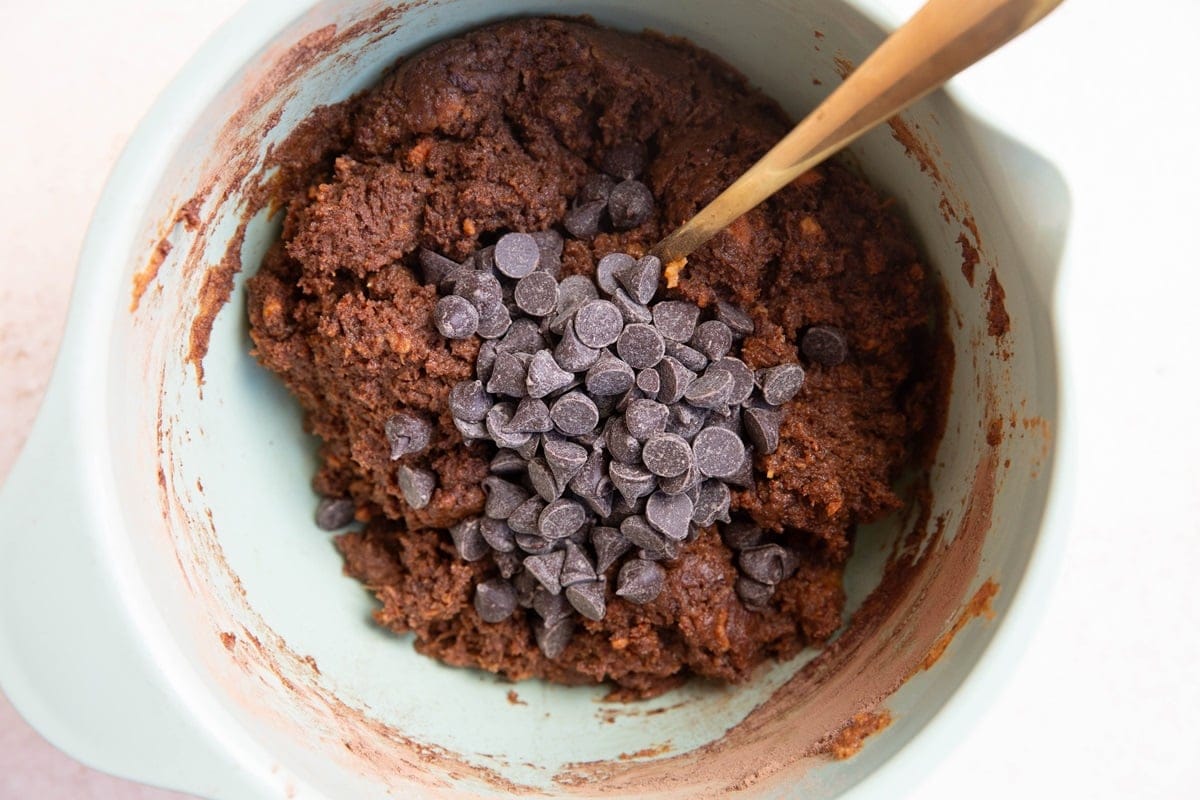 Mixing bowl of sweet potato cookie dough with chocolate chips on top, ready to be mixed in.