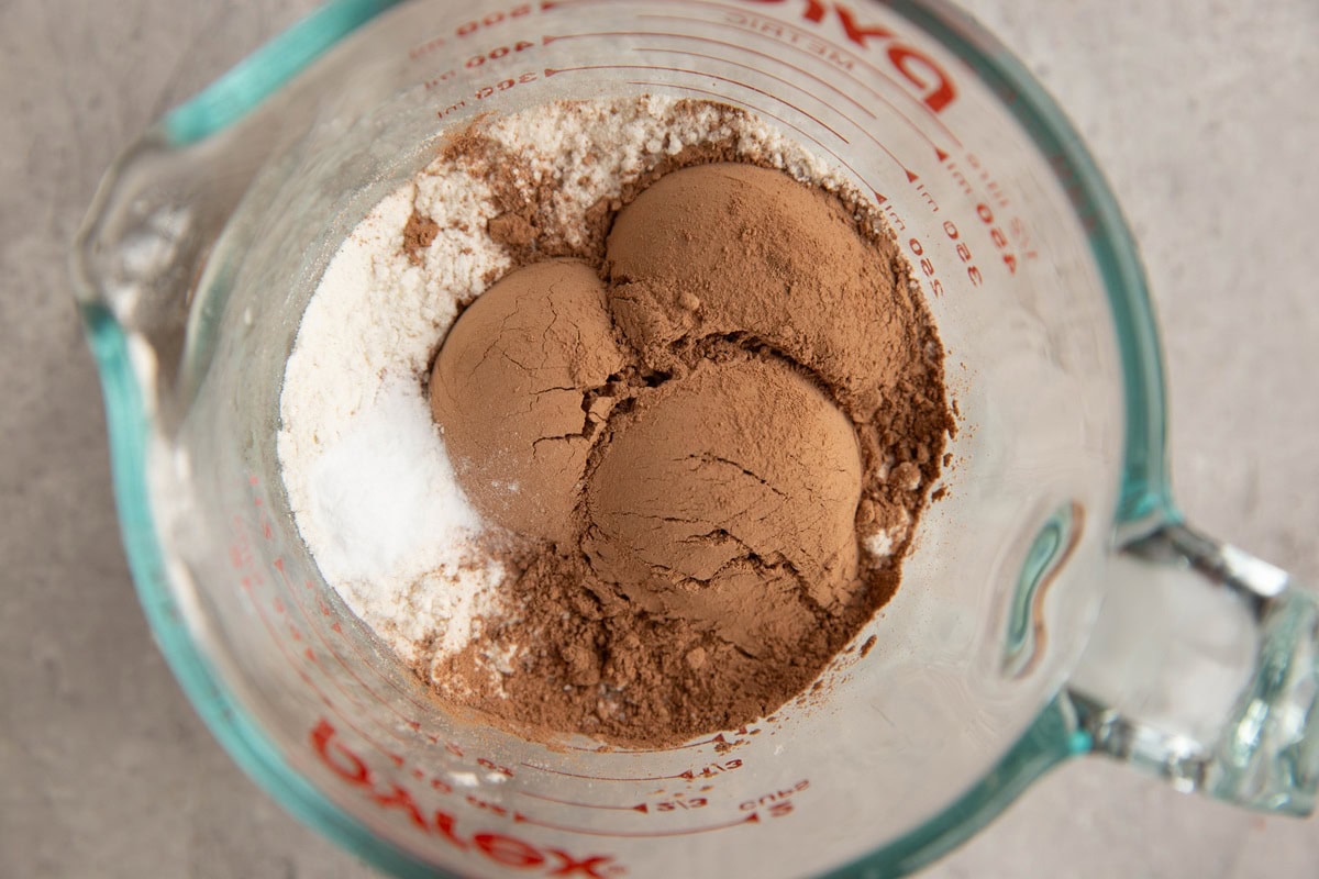 Measuring cup of flour, cocoa powder, and baking powder.