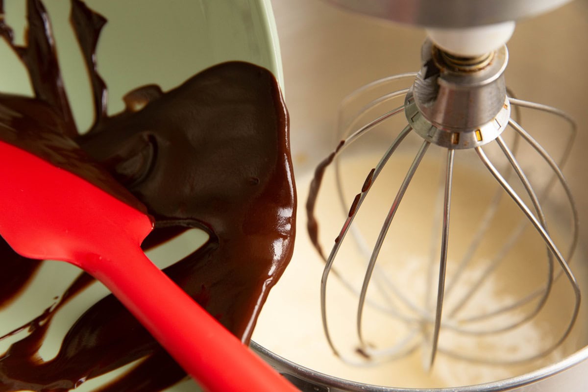 Pouring the chocolate mixture into the mixer with the egg mixture.