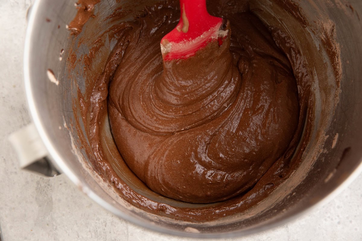 Rubber spatula inside a mixing bowl with brownie batter.