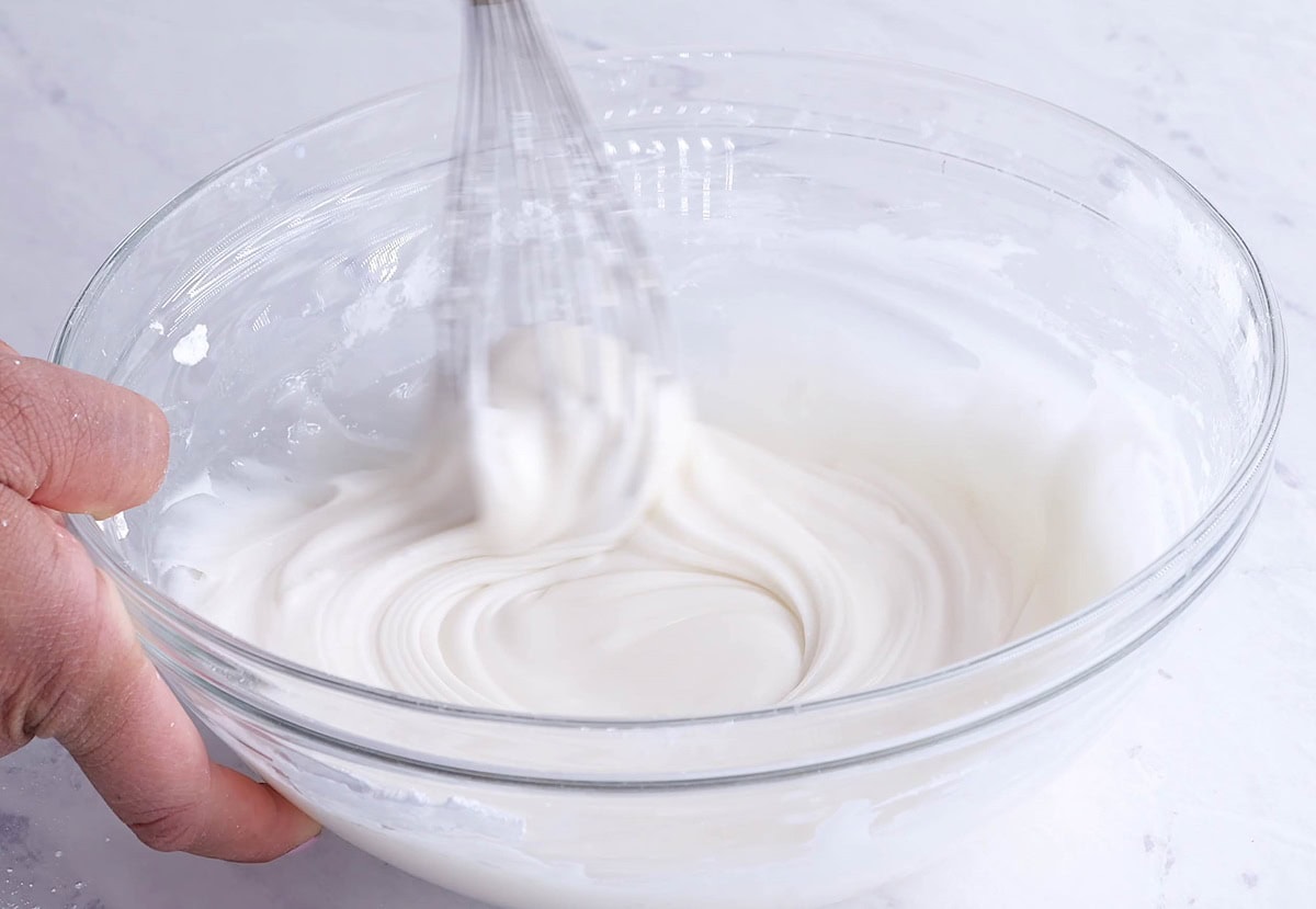 Hand mixing a bowl of royal icing.