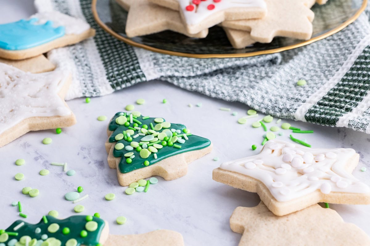 Gluten-free sugar cookies in the shape of Christmas trees and stars decorated on a marble surface.