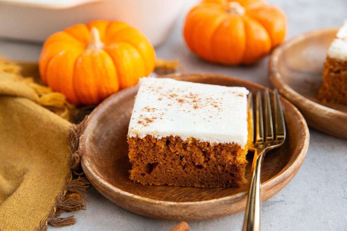 Two plates of pumpkin cake with small pumpkins in the background.