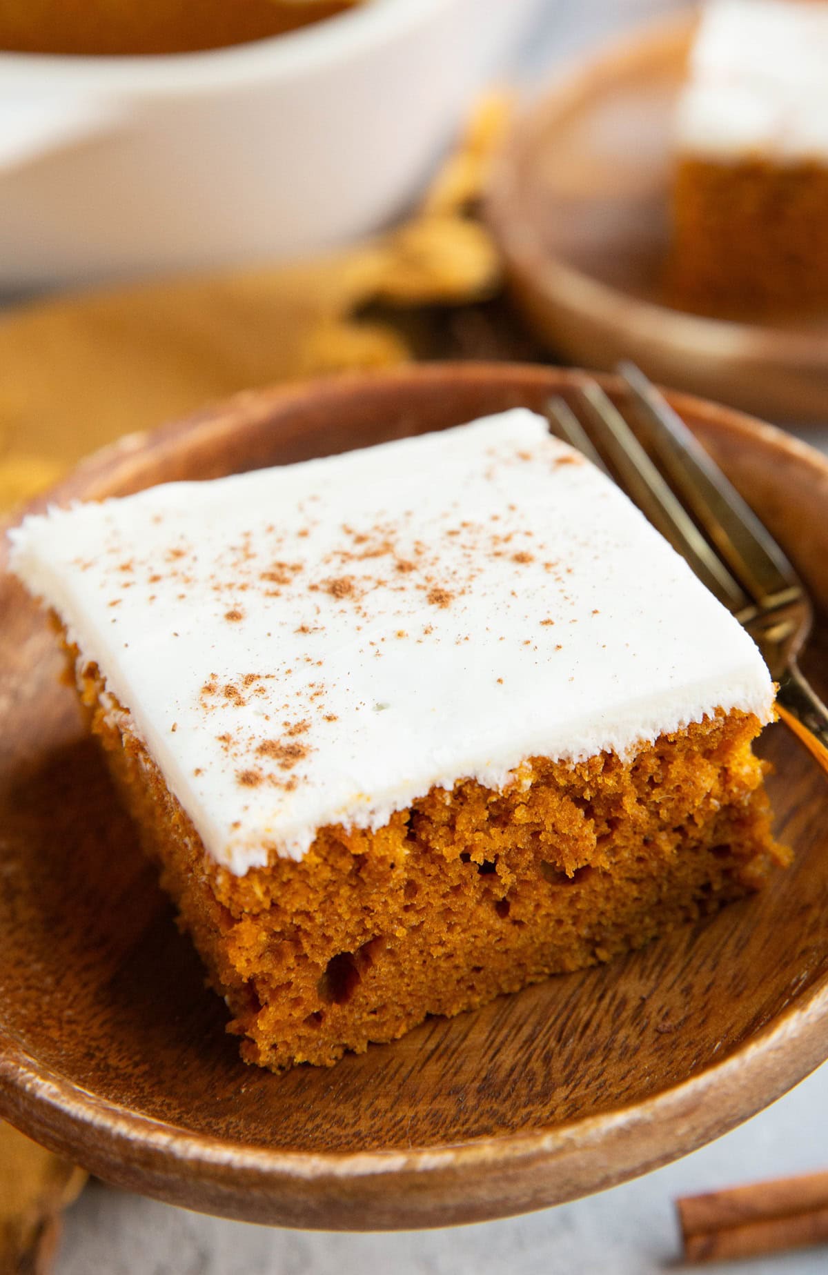 Big slice of pumpkin cake on a wooden plate.