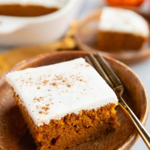 Two plates of slices of pumpkin cake frosted with cream cheese frosting, ready to eat.