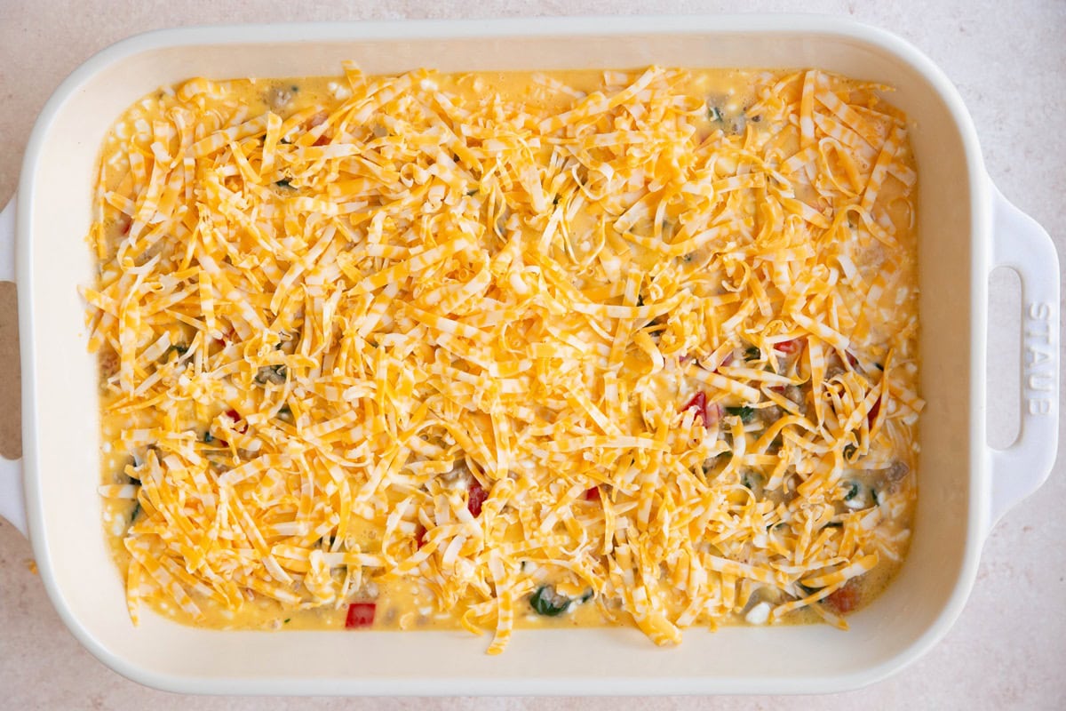 Grated cheese sprinkled on top of casserole ingredients for a cheesy topping.