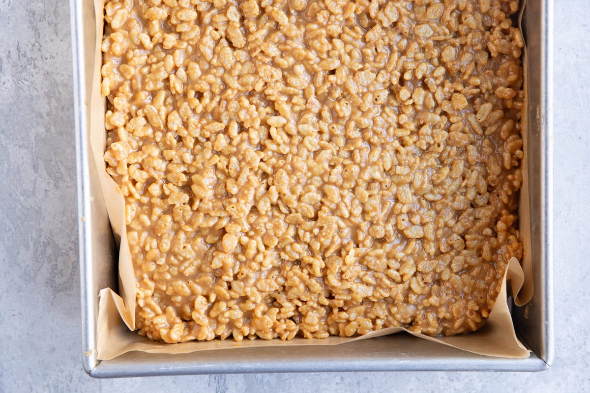 9-inch baking pan with peanut butter rice krispie layer pressed into an even layer.