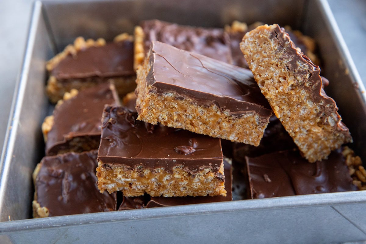 Pile of scotcheroo bars cut into squares inside of a baking pan, ready to serve.