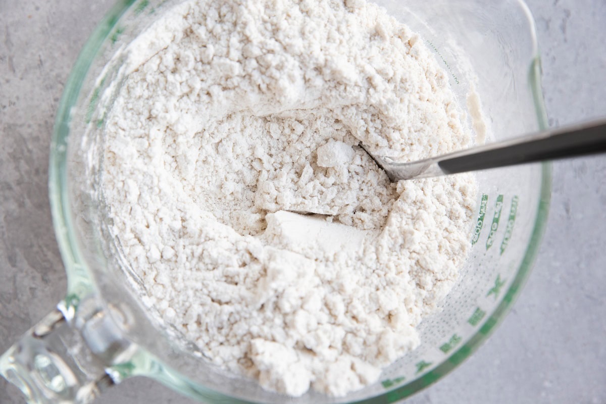 Large measuring cup full of a flour mixture.