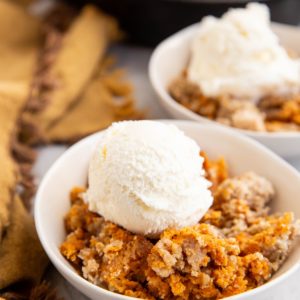 Sweet potato crisp in two bowls with scoops of ice cream on top.