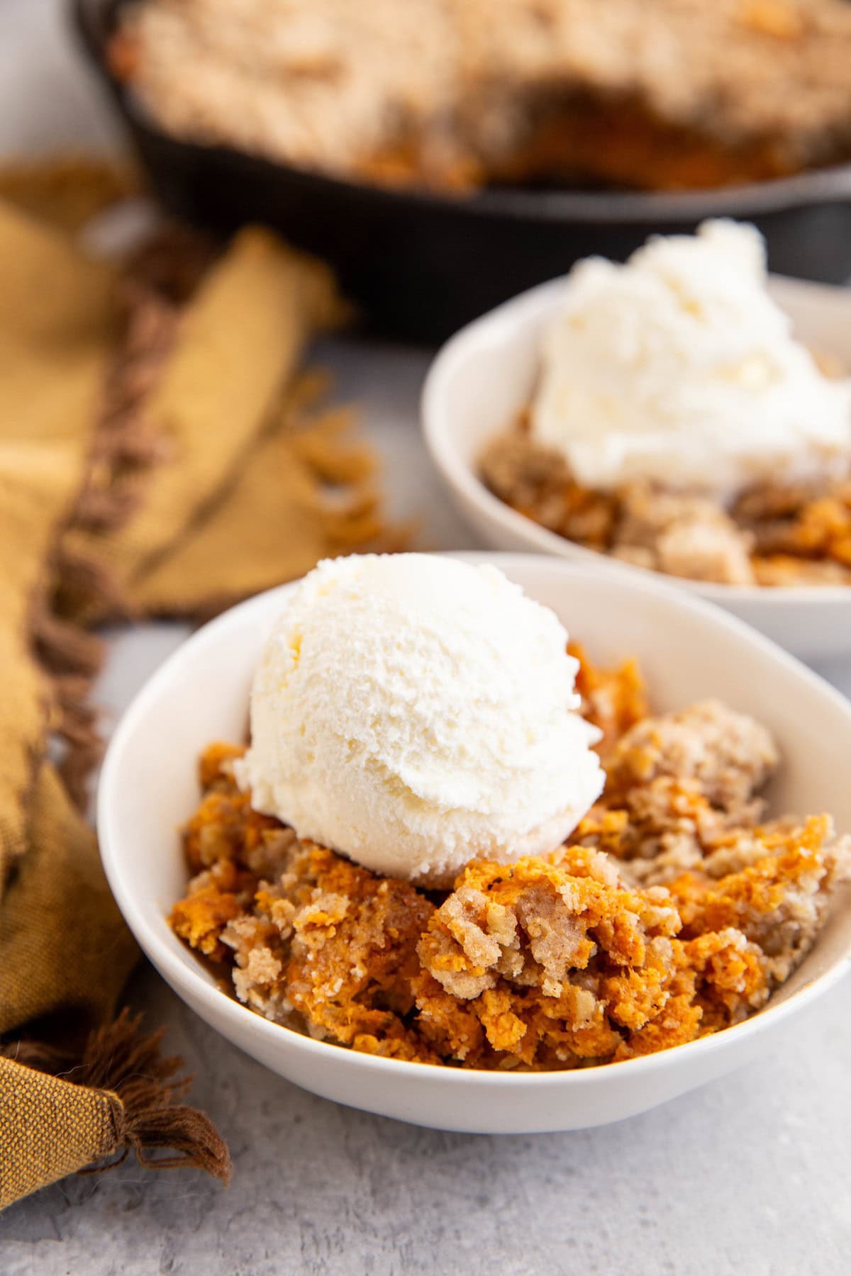 Sweet potato crisp in two bowls with scoops of ice cream on top.