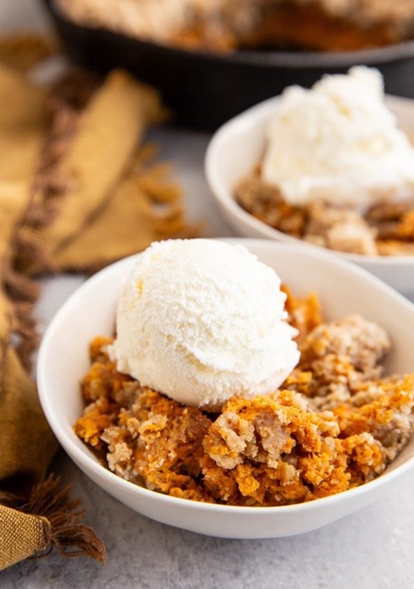 Sweet potato crumble in two bowls with scoops of vanilla ice cream on top.