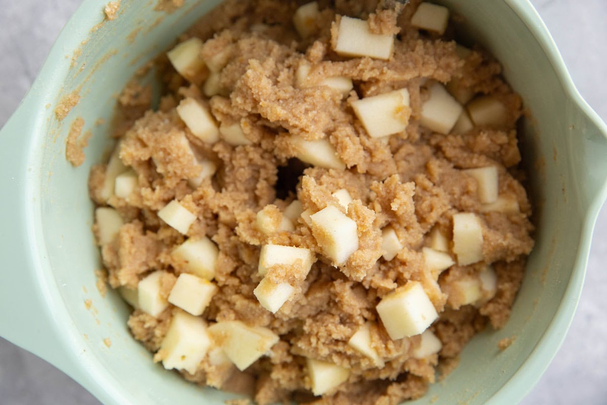 Scone dough in a mixing bowl with chunks of apples mixed in to make apple scones.