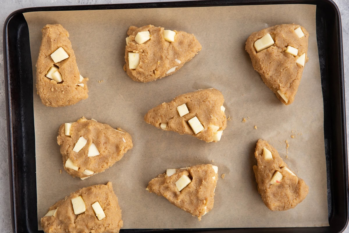 Parchment-lined baking sheet with scone dough on top, ready to bake.