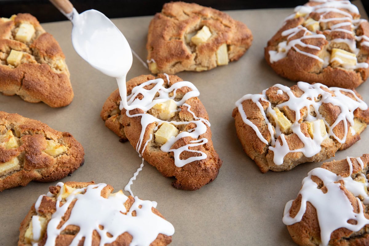 Spoon drizzling glaze over apple scones.