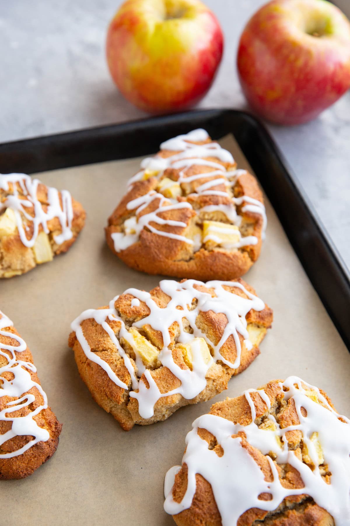 Baking sheet of almond flour apple scones with fresh apples in the background.