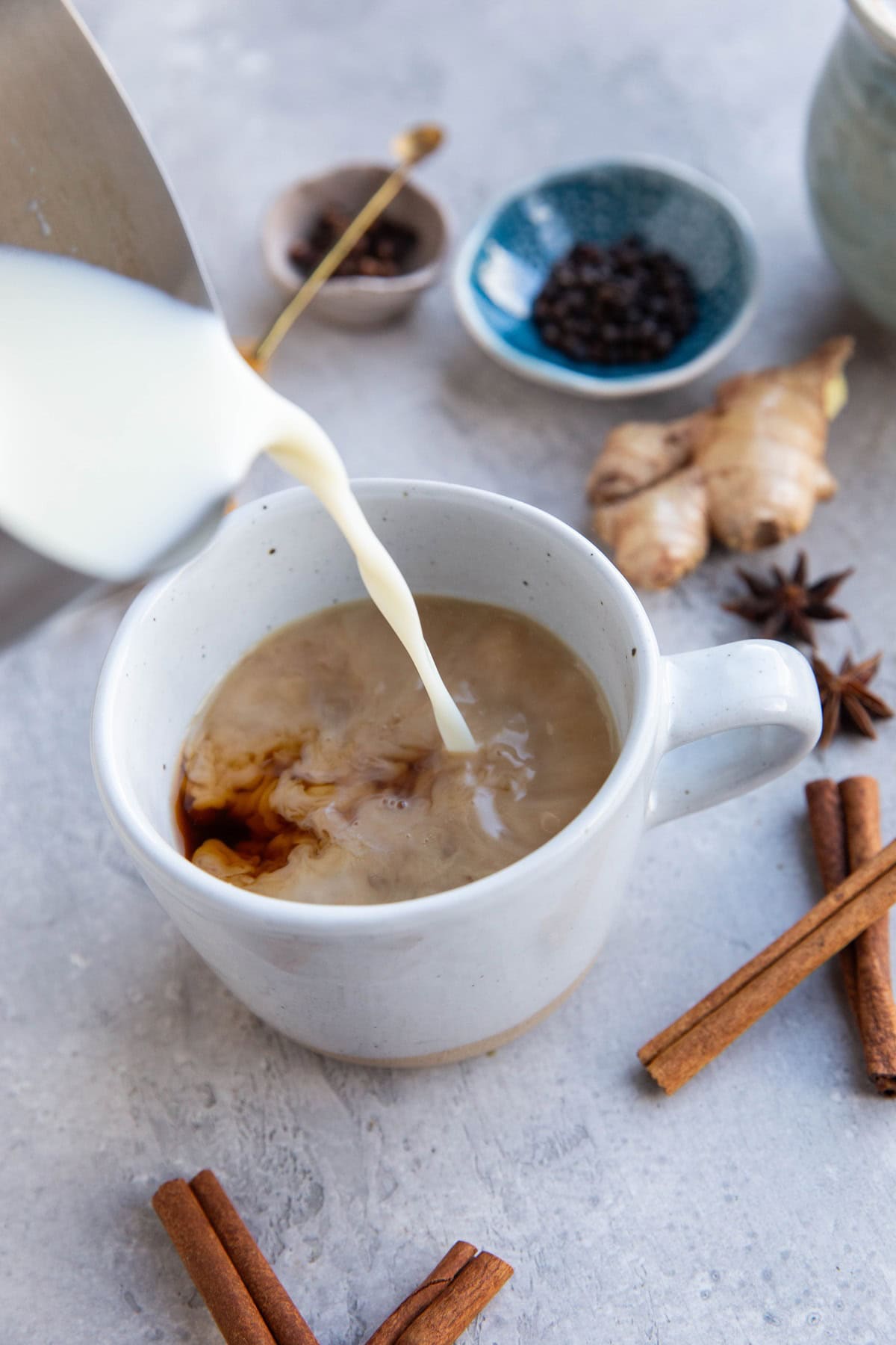 Milk frother pouring milk into a mug with chai tea.