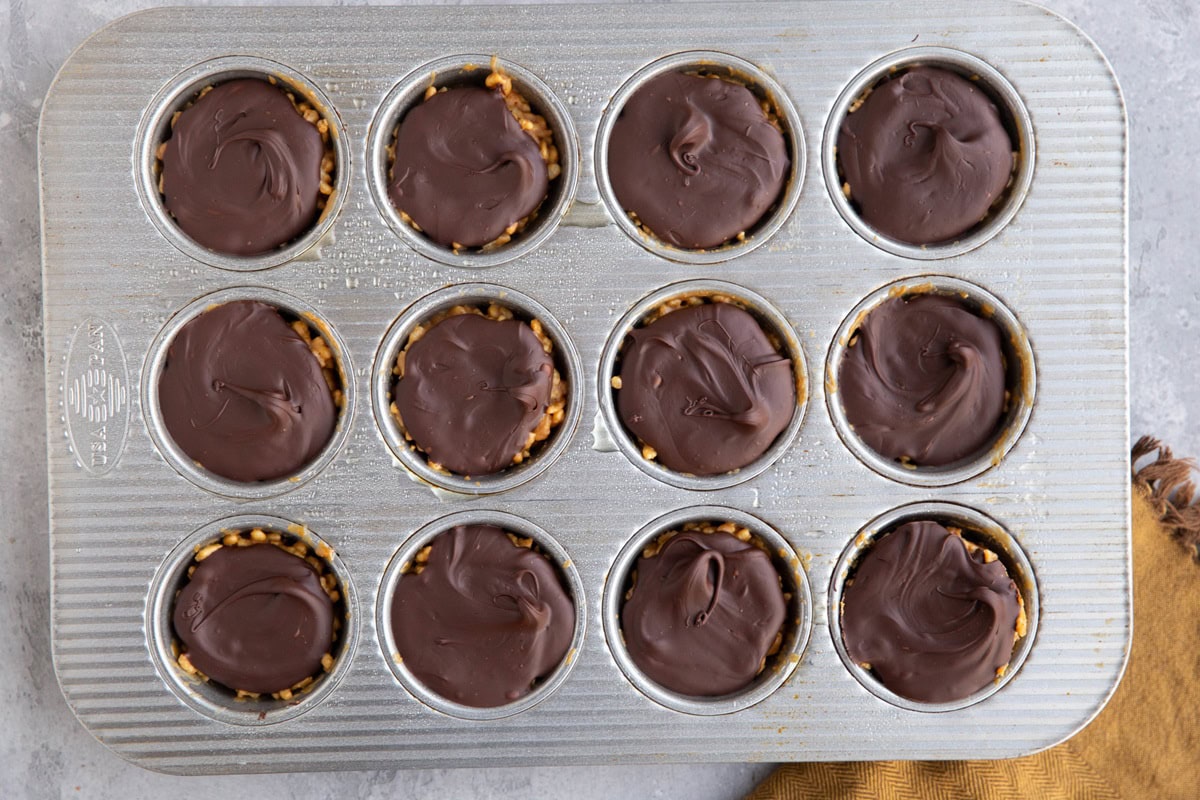 Muffin tin with peanut butter rice crispy cups covered in chocolate